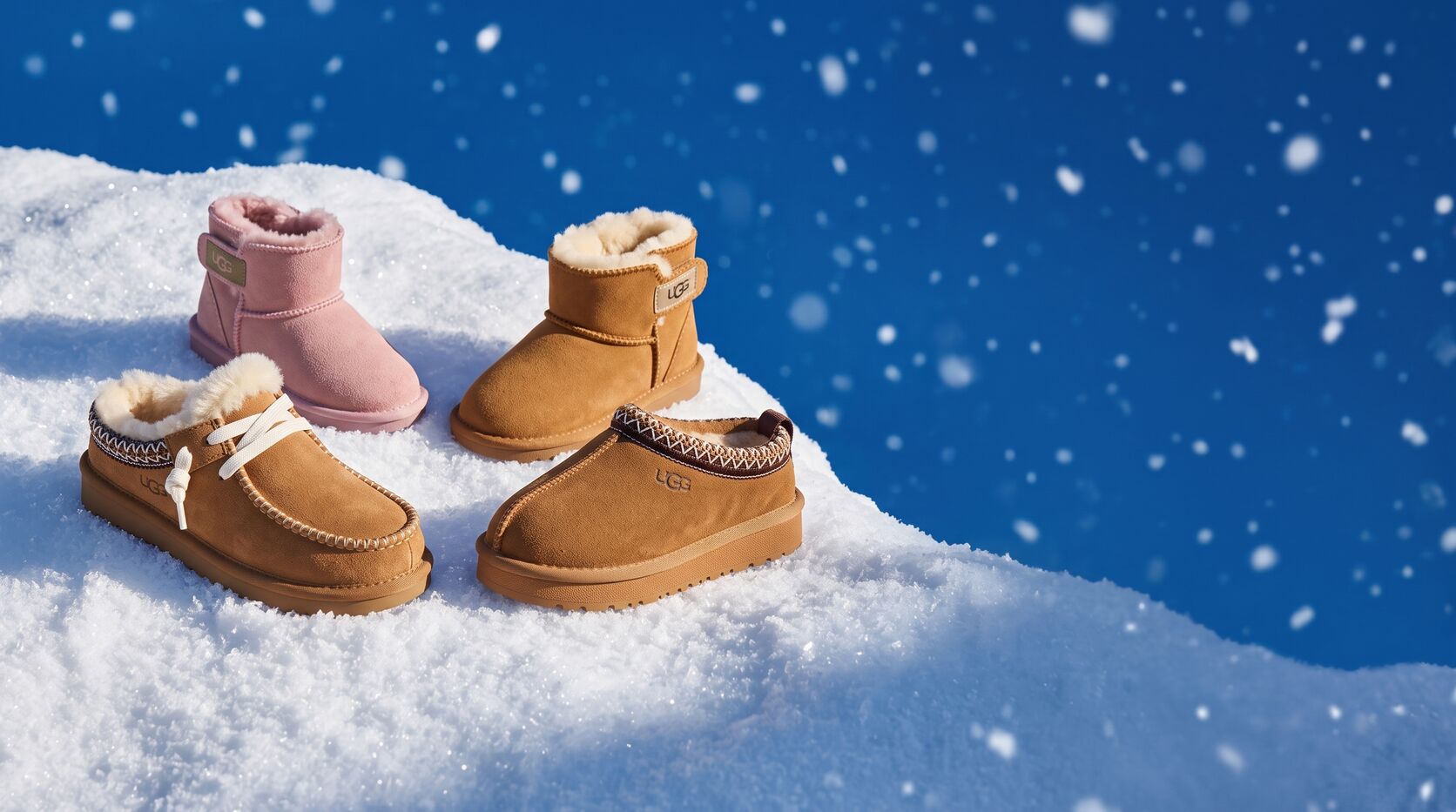 נעלי UGG לילדים בחום ובוורוד על שלג, ברקע שמיים כחולים ושלג יורד